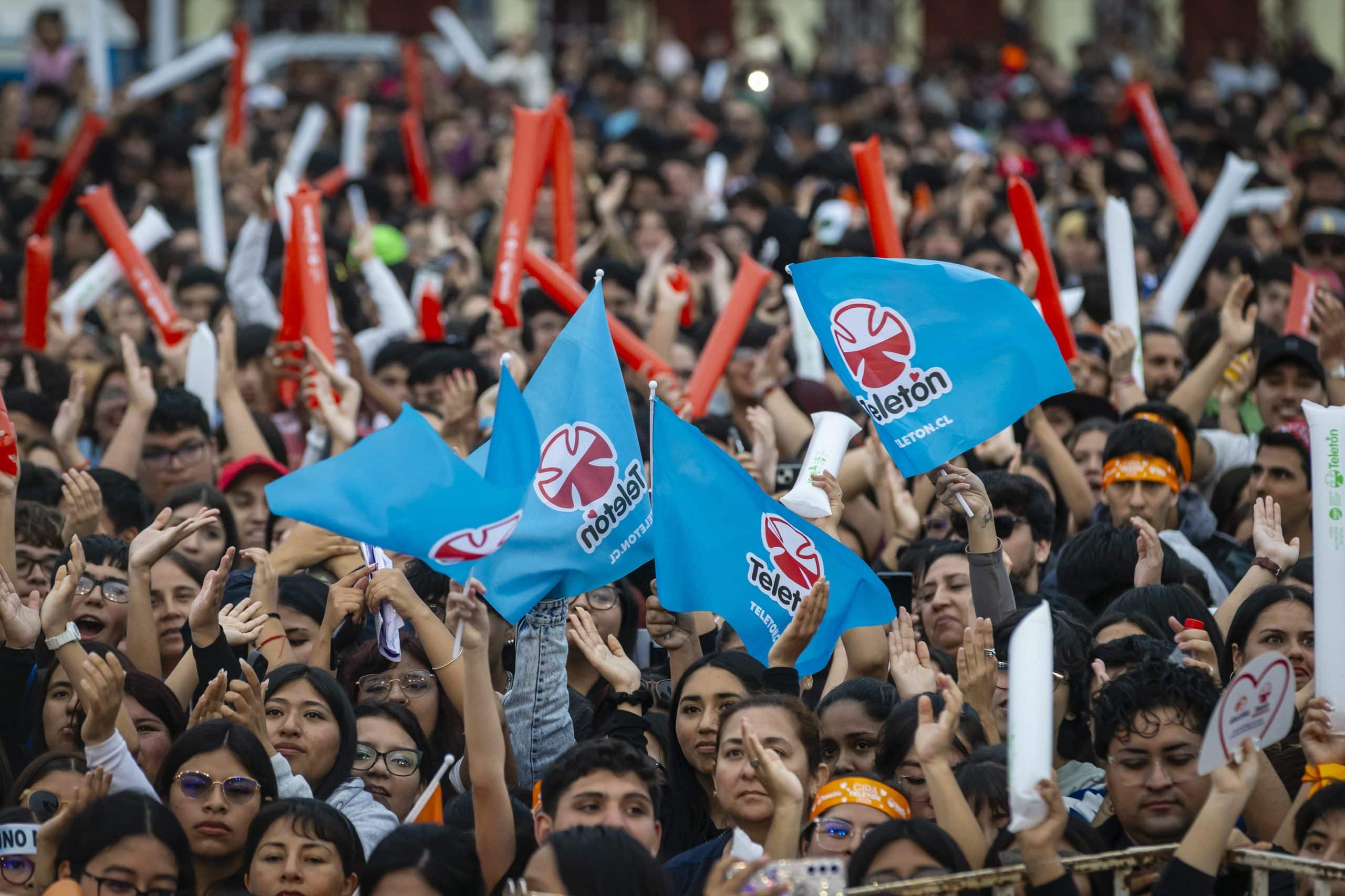 Público con banderas de Teletón y las manos en alto en un show de la Gira Teletón